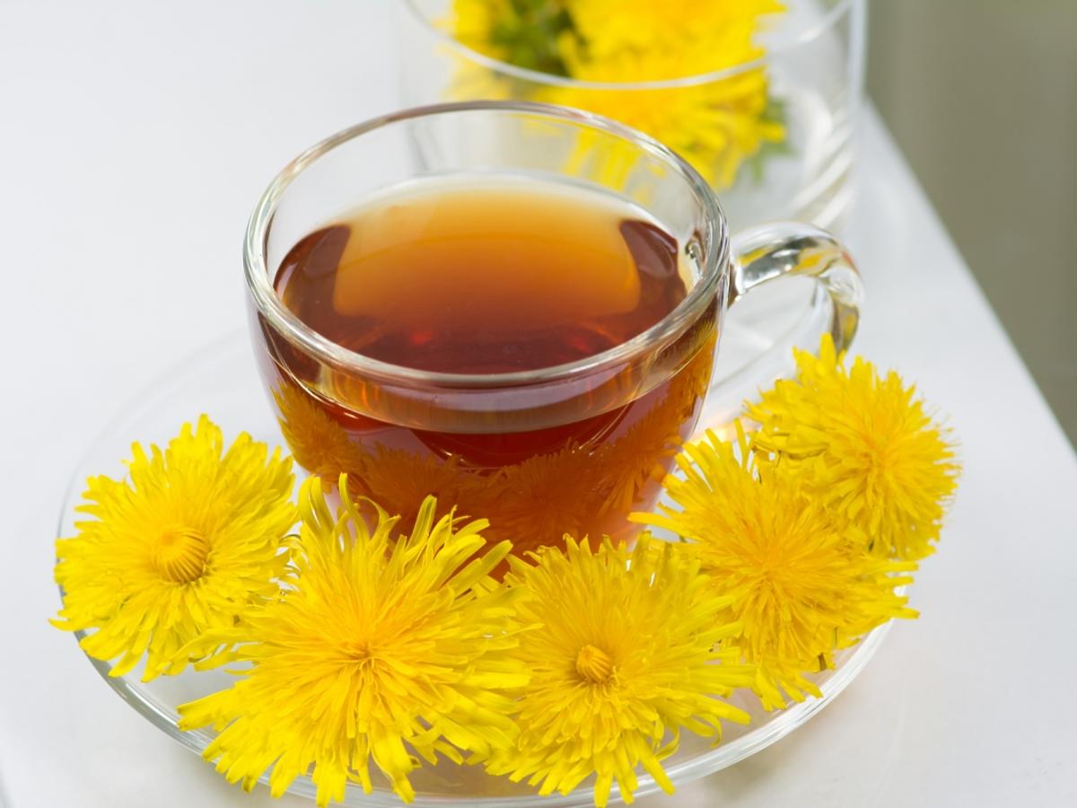 Szklanka z herbatą i kwiaty mniszku.