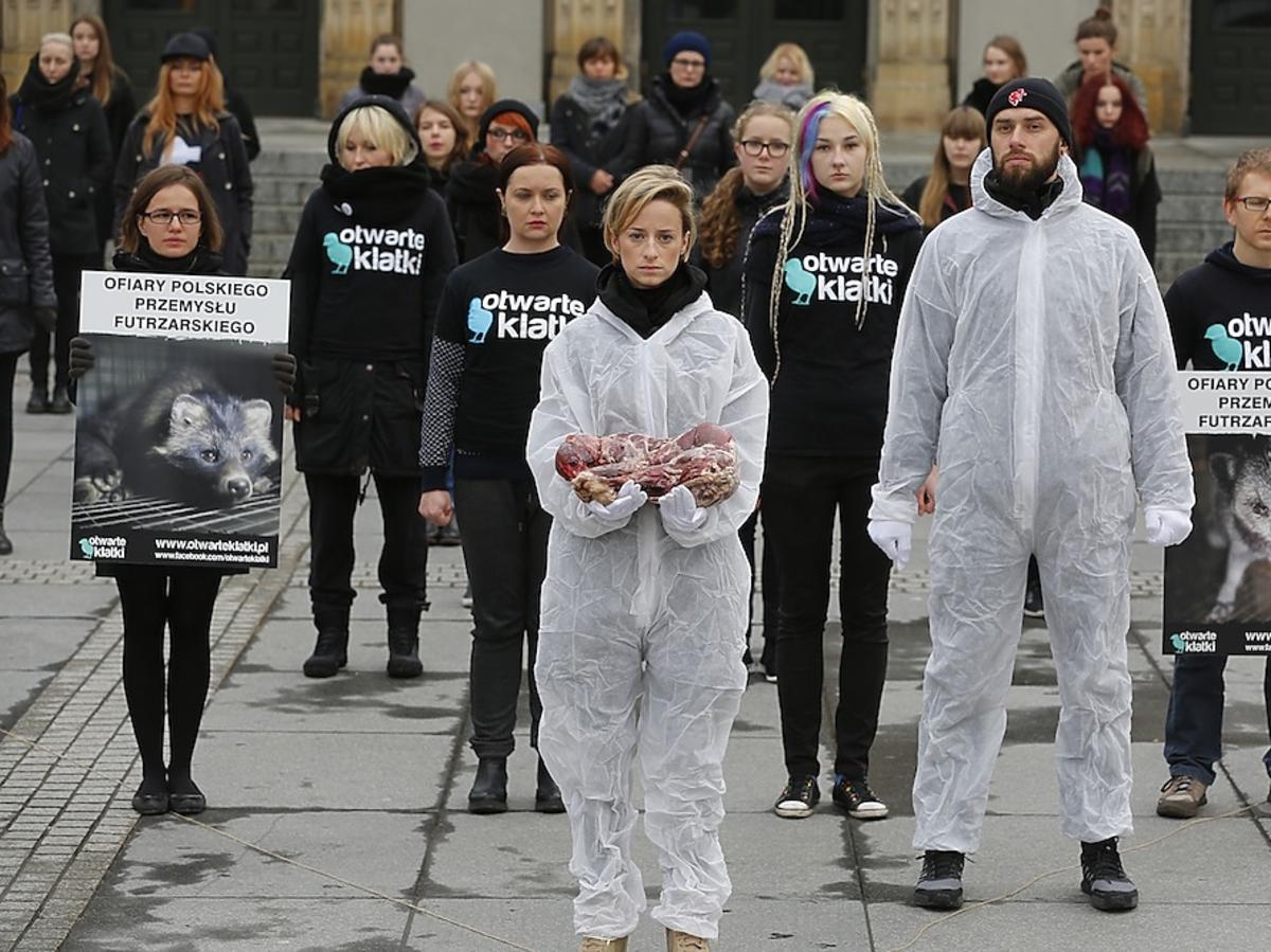 Urszula Dębska w bialym kubraku na manfestacji trzyma odarte zwierze ze skóry