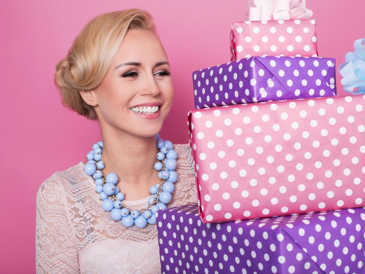 uśmiechnięta blondynka trzyma pudła z prezentami