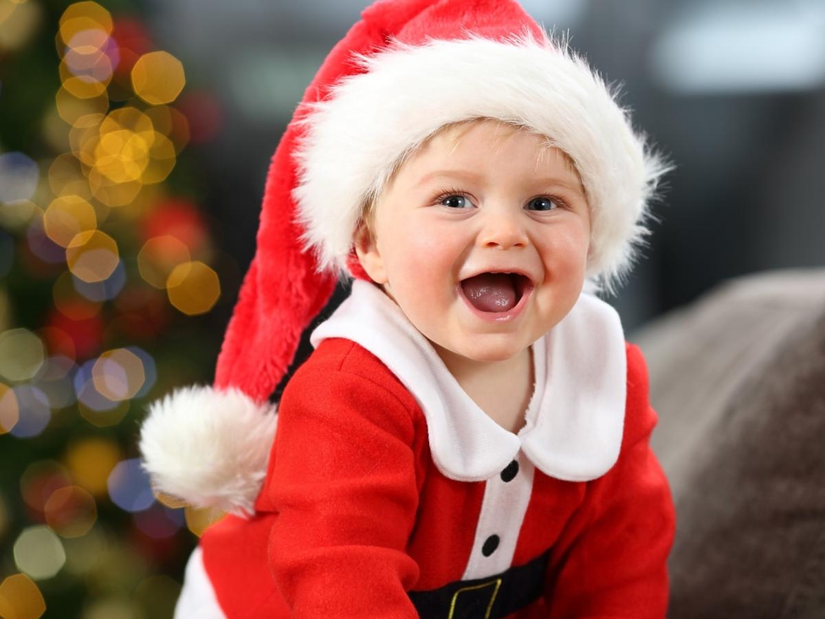 Uśmiechnięte niemowlę w czapce św. Mikołaja.