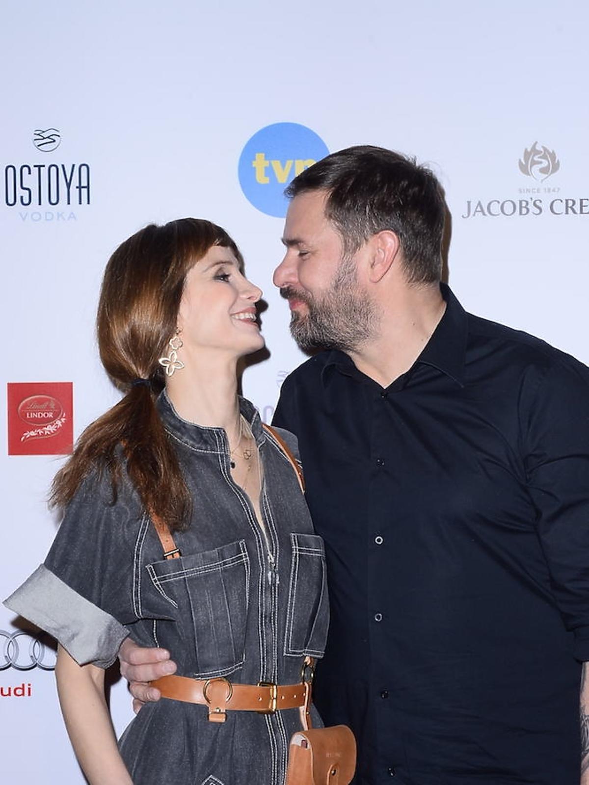 Viola Kołakowska w czarnym kobinezonie i Tomasz Karolak w czarnej koszuli na ściance