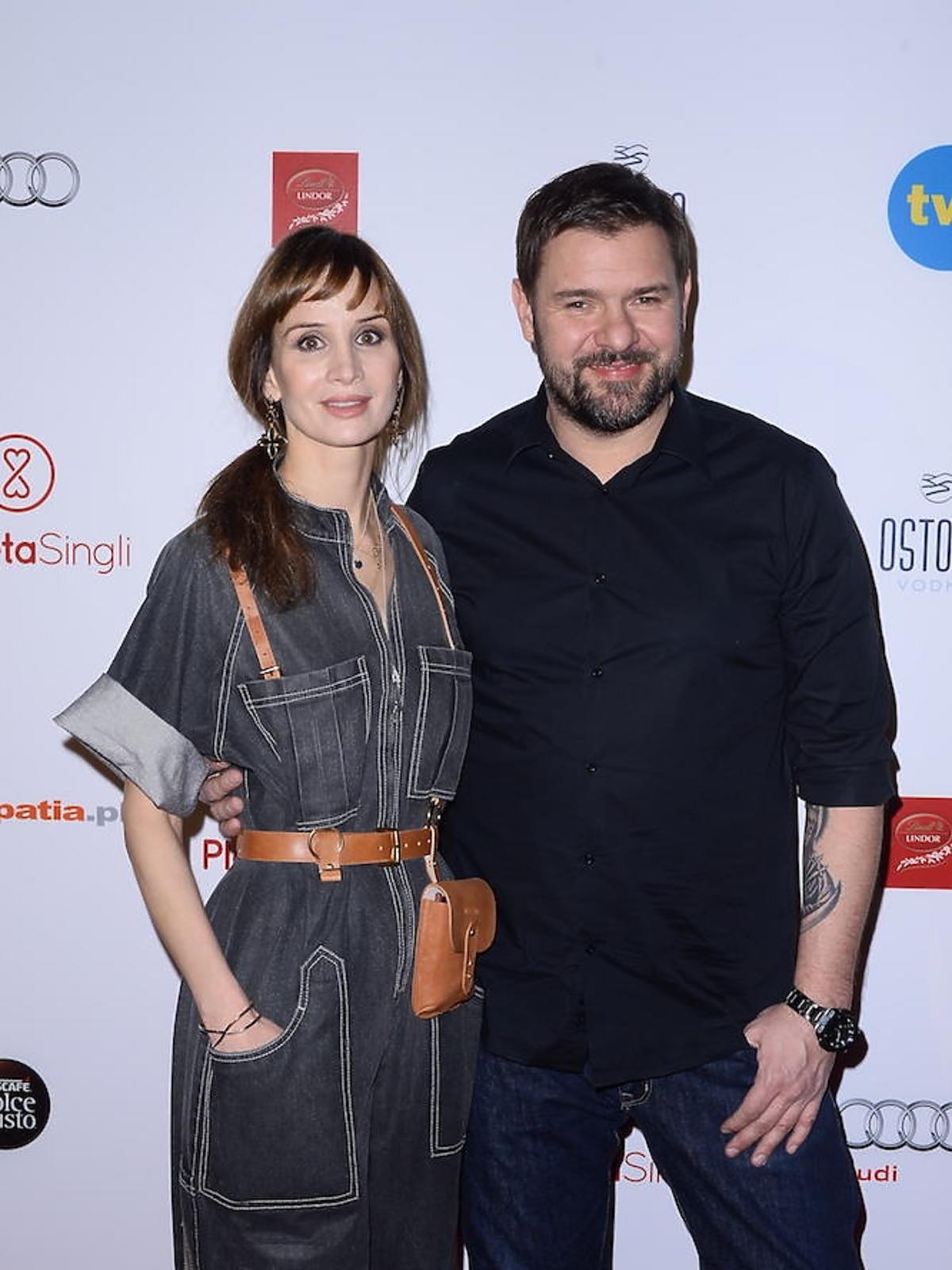 Viola Kołakowska w czarnym kobinezonie i Tomasz Karolak w czarnej koszuli na ściance