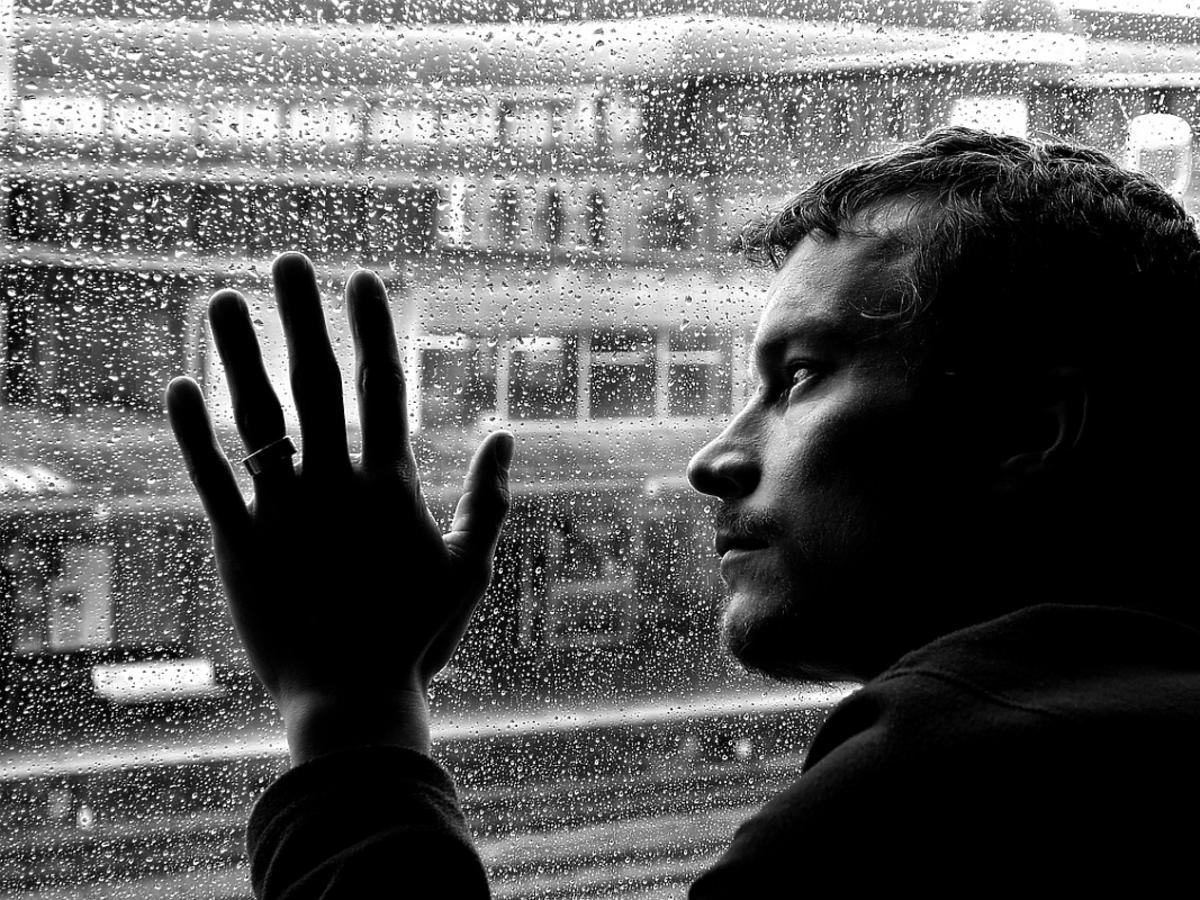 Zasmucony mężczyzna patrzy przez okno