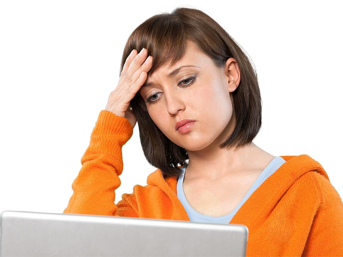 Zmartwiona kobieta patrzy na laptopa