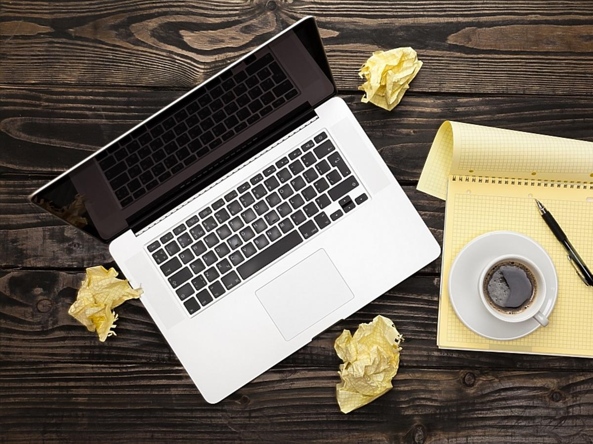 Zmięte kartki papieru, długopis i laptop.